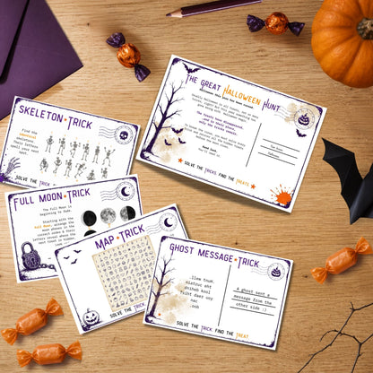 Five printable Halloween-themed activity cards arranged on a wooden surface with candy, a pumpkin, and black bat decorations around them. The cards include activities such as Skeleton Trick, Full Moon Trick, Map Trick, Ghost Message Trick, and The Great Halloween Hunt.