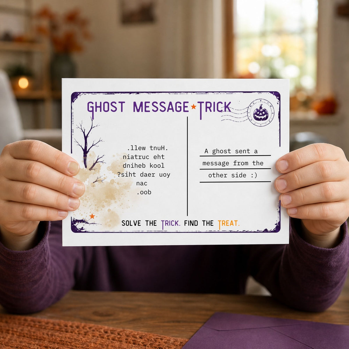 A person holds a printed ghost message postcard with a spooky tree illustration and riddle text, photographed in a warm indoor setting with a blurred background.