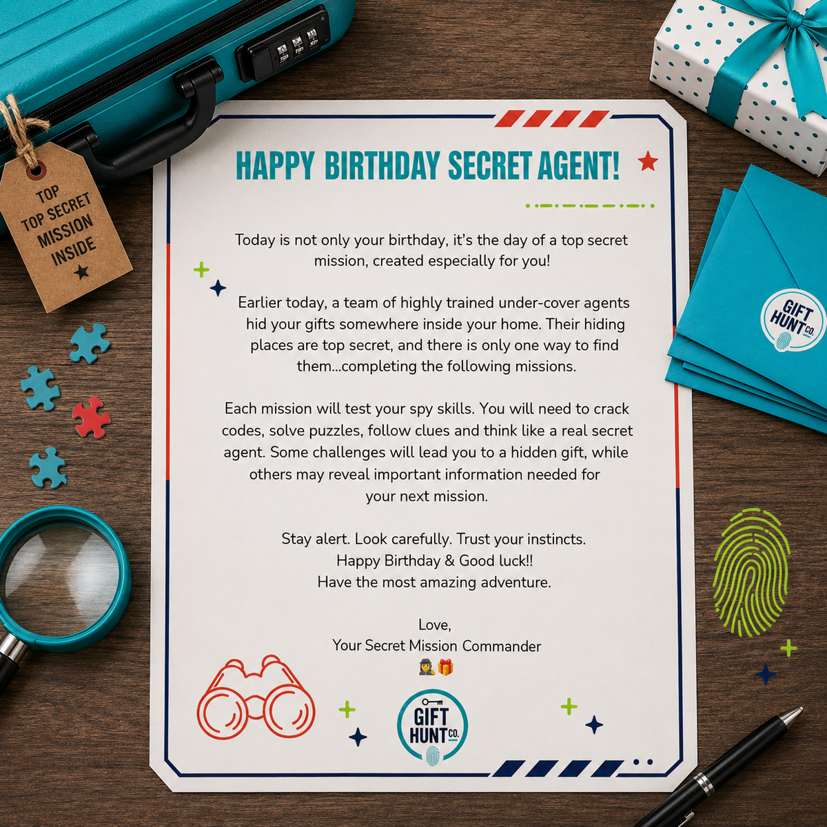 A flat-lay birthday card reading 'HAPPY BIRTHDAY SECRET AGENT!' with playful spy-themed illustrations, surrounded by a suitcase, magnifying glass, puzzle pieces, pen, and gift box on a wooden surface.